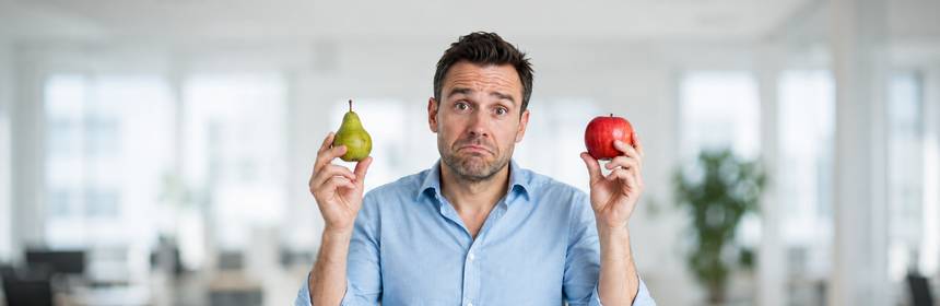 Ratloser Mann im Büro hält eine Birne und einen Apfel und vergleicht Unvergleichbares